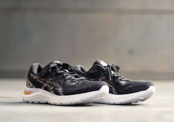 Scarpe da corsa Asics Gel Cumulus 23 nere con dettagli in bronzo e suola bianca, pronte per ogni avventura.