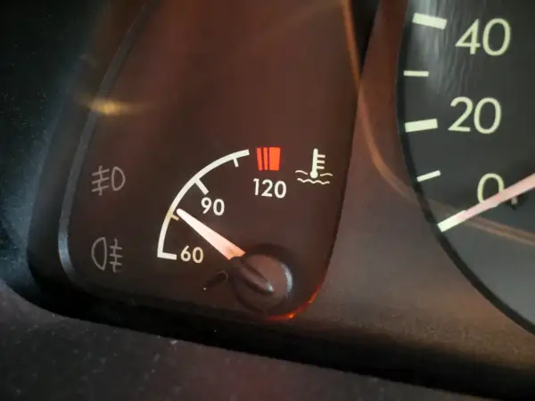 Le témoin de température moteur s'allume, indiquant une **cause surchauffe moteur essence**. Le thermomètre est proche de 120°C.