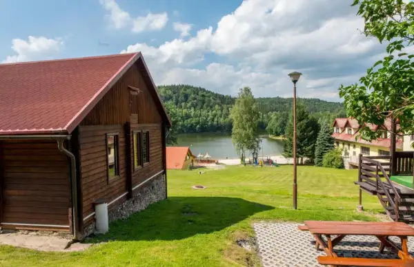 Drewniane domki nad jeziorem w Dolnośląskim. Piękny krajobraz z zielonymi wzgórzami i jeziorem.