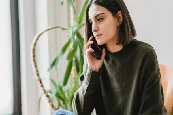Młoda kobieta, jobseeker, rozmawia przez telefon, jej mina sugeruje rezygnację.