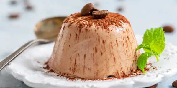 En krämig italiensk pannacotta, pudrad med kakao och toppad med kaffebönor. En frisk myntakvist ger en fin kontrast.