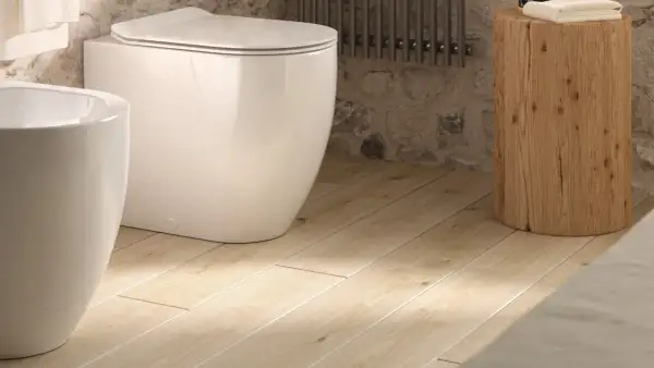 Bagno moderno con vaso e bidet bianchi su un caldo pavimento in pvc per bagno, opinioni positive per questo stile.