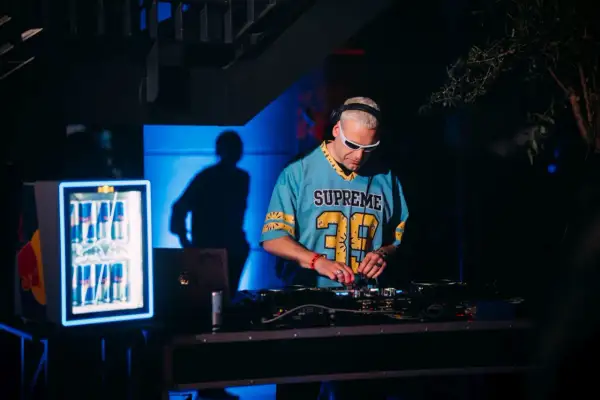 DJ Inox w niebieskiej koszulce z numerem 39 gra muzykę na konsoli DJ-skiej.