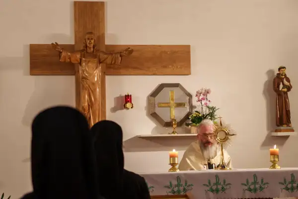 Ksiądz z brodą odprawia nabożeństwo w pierwszy czwartek miesiąca. Widać krzyż, figurę świętego i monstrancję.