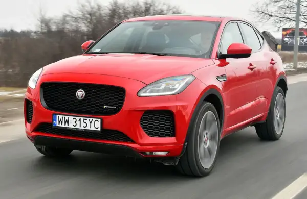 Czerwony Jaguar E-Pace pędzi po drodze, ukazując swoje sportowe linie i charakterystyczny grill.