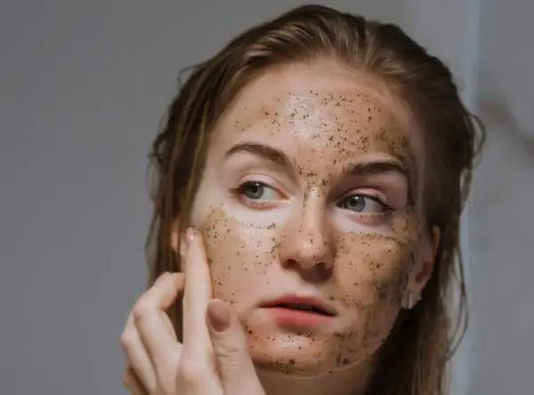 Una donna applica uno scrub viso, scoprendo i benefici di una pelle liscia e luminosa.
