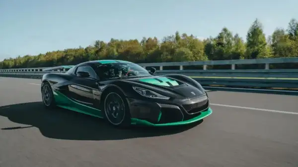 Czarny Rimac Nevera z zielonymi akcentami pędzi po torze, demonstrując swoją moc w przyspieszeniu 0-100 km/h.