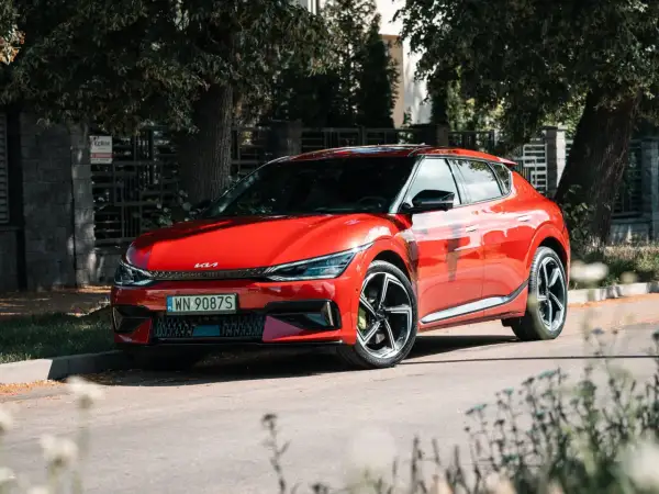 Czerwone Kia EV6 GT, gotowe do sprintu 0-100 km/h, zaparkowane przy ulicy w słoneczny dzień.