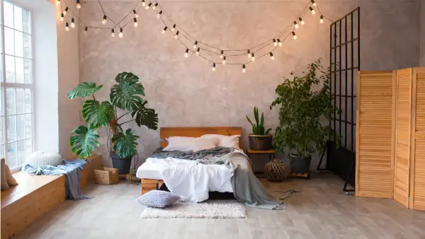Przytulna sypialnia boho loft z łóżkiem, roślinami i girlandą świetlną.