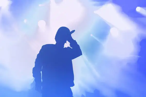 Silhouette di un rapper con microfono, luci blu e bianche sullo sfondo. Le origini di Tony Boy.