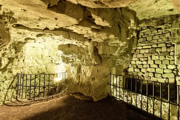 Intérieur des boves d'Arras, un réseau de galeries souterraines aux murs de pierre brute et de briques, éclairées par une lumière jaune.