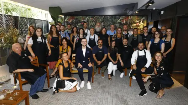 Grupo diverso posa con delantales "es.table Zaragoza" en un evento.