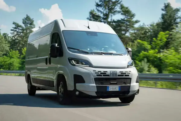 Un fourgon Fiat Ducato 2.3 Multijet 140 Euro 6 roule sur une route bordée d'arbres.