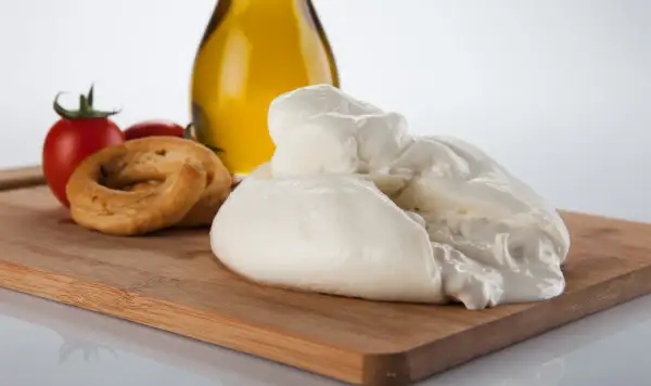La burrata, un tesoro cremoso, si presenta su un tagliere con pomodorini, taralli e olio d'oliva.