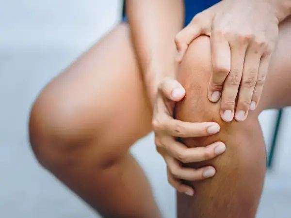Hände umfassen ein schmerzendes Knie. Was tun bei Knieschmerzen?