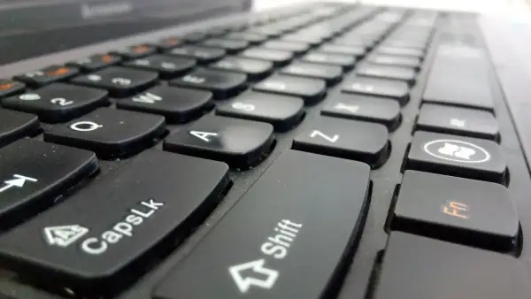 Primer plano de un teclado de portátil. La tecla Shift está en el centro, lista para escribir en mayúsculas.