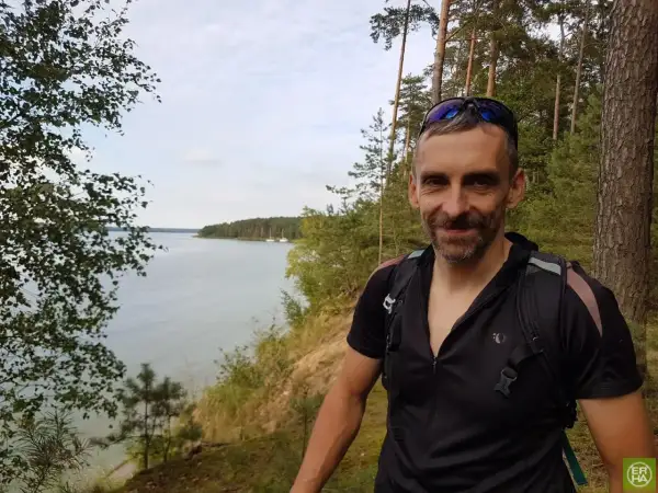 Uśmiechnięty rowerzysta na tle malowniczego zalewu sulejowskiego. Trasa rowerowa wokół zalewu sulejowskiego oferuje piękne widoki.