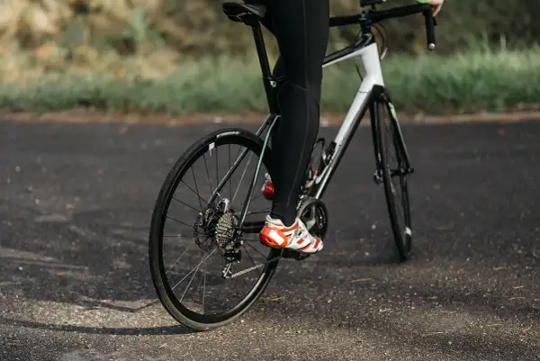 Rowerzysta w sportowych butach pedałuje, utrzymując optymalną kadencję rower.