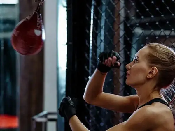 A woman trains with a speed bag, practicing her punches. This image shows a key element of how to make a speed bag workout effective.