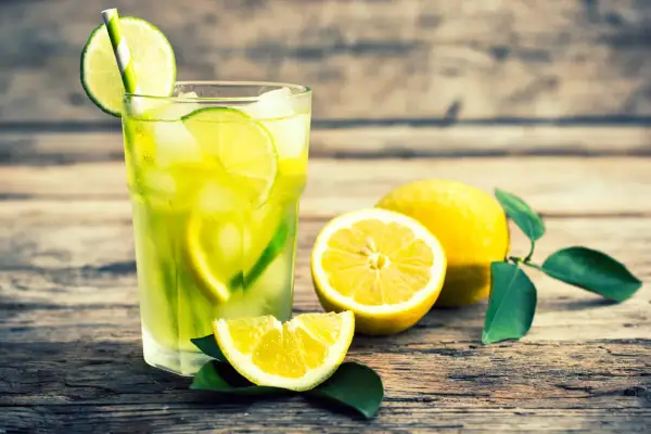 Vaso de limonada refrescante con rodajas de lima y limón, mostrando la diferencia entre lima y limón.