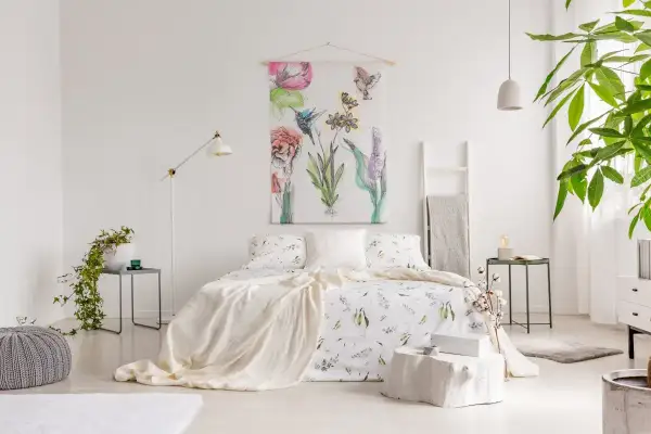 Sypialnia w stylu shabby chic z pościelą w kwiaty, narzutą i obrazem z ptakami i kwiatami.