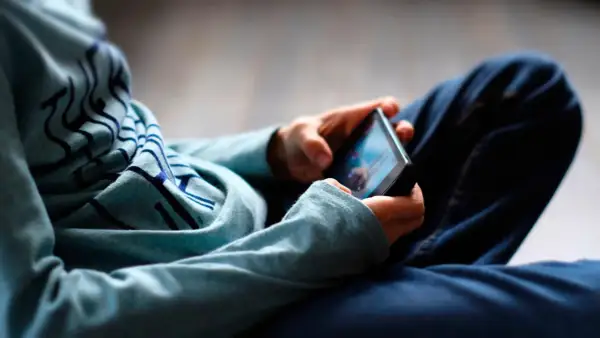 Ein digitaler Mensch, vertieft in sein Smartphone. Die Hände halten das Gerät, während der Blick auf den Bildschirm gerichtet ist.