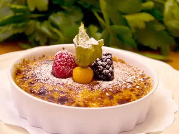 En krämig crema catalana toppad med bär och pudrat socker, en ljuvlig dessert.