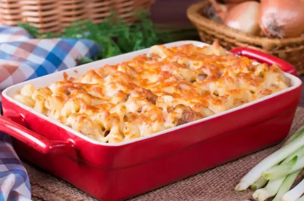 Zapiekanka makaronowa z serem w czerwonym naczyniu.
