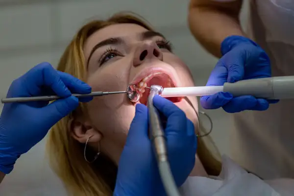 Dentysta pomaga zabezpieczyć ząb po wypadnięciu plomby, używając narzędzi stomatologicznych.