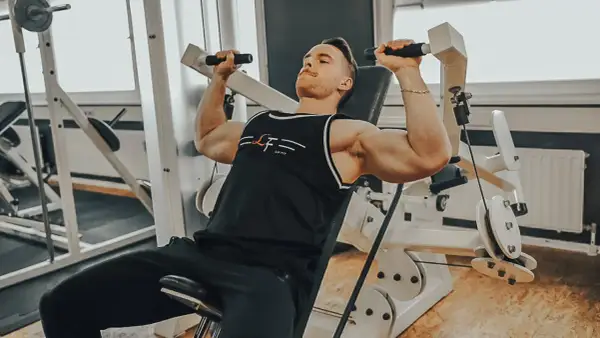 Mann trainiert Schultern an einer Maschine, ein intensiver superset workout für maximale Ergebnisse.
