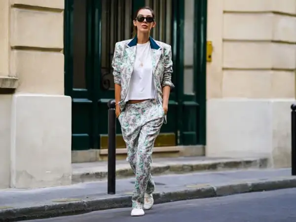 Donna con tailleur floreale e scarpe basse cammina per strada, con un'aria disinvolta e chic.