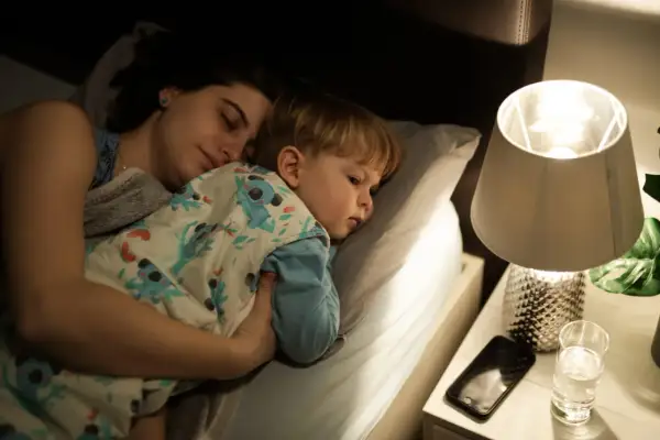 Mamma e figlio dormono abbracciati a letto, avvolti in una coperta con koala. Un momento di pace prima che i miei figli si sveglino.