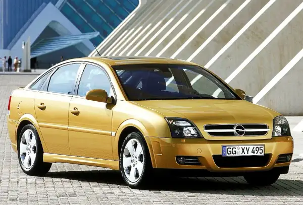 Złoty Opel Vectra C 1.9 CDTI 120 KM prezentuje się elegancko na tle nowoczesnej architektury. Opinie o tym modelu często podkreślają jego komfort i oszczędność.