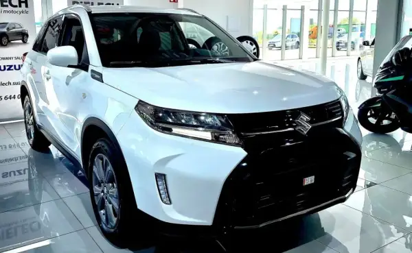 Biały Suzuki Vitara Hybrid błyszczy w salonie, gotowy na miejskie przygody.