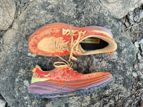 Kolorowe buty Hoka Speedgoat 6 na kamieniu. Hoka to firma znana z amortyzacji i komfortu.