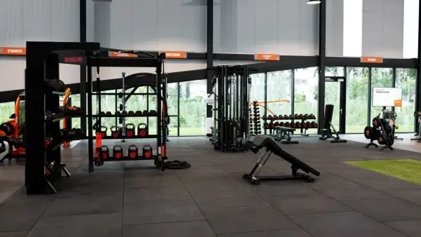 Estanterías con pesas, kettlebells y equipo de entrenamiento funcional en un gimnasio. Todo listo para tu **basic fit**.