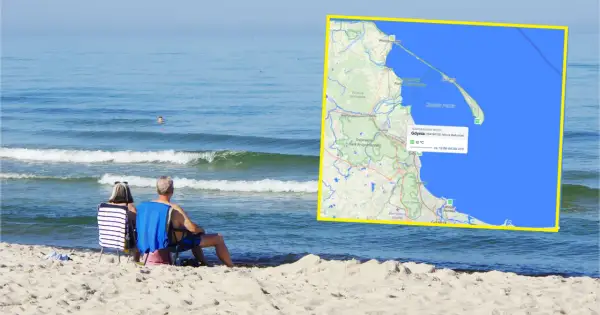 Para siedzi na plaży, patrząc na morze. Na mapie widać, że ile stopni ma teraz woda w Bałtyku: 12°C w Gdyni.
