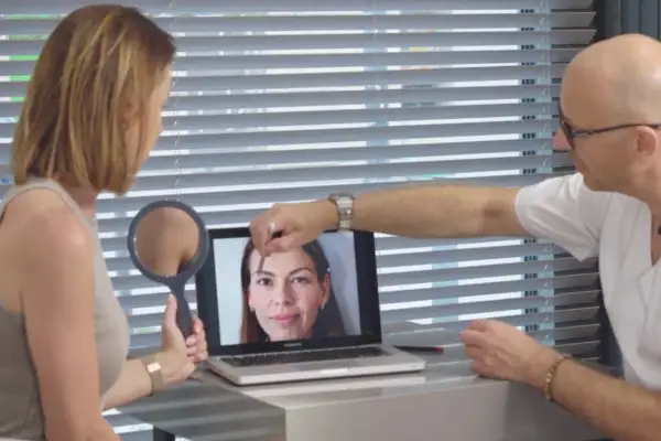 Lekarz pokazuje pacjentce na laptopie zdjęcie twarzy, analizując skórę.
