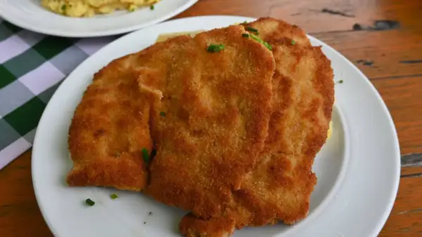 Zwei goldbraune Schnitzel auf einem Teller, garniert mit Schnittlauch. Ein Klassiker der Berliner Küche, der Appetit macht.