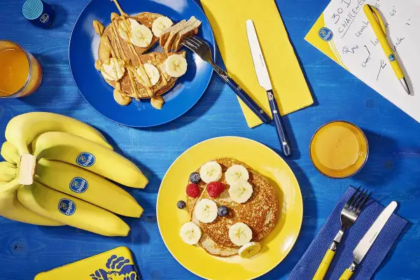 Pancakes con banana dopo allenamento, un pieno di energia. Frutta fresca e succo d'arancia per recuperare al meglio.