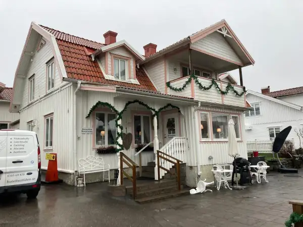 Vitt hus med rosa detaljer och juldekorationer. Skylt visar "Reception Restaurang". Kanske en titt på restaurang Solliden meny?