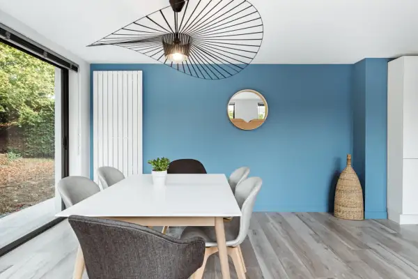 Un mur bleu vif illumine cette salle à manger moderne. Quel mur peindre en couleur ? Celui-ci, sans hésiter !