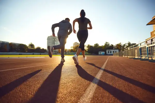 Deux coureurs sur une piste, le soleil couchant projette leurs ombres. Ils s'entraînent, peut-être pour savoir que veut dire EF en course à pied.