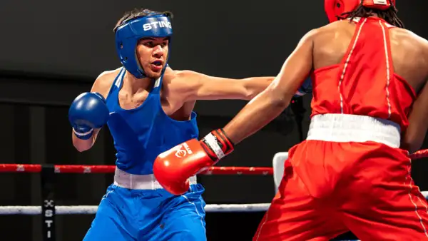 Two young boxers in a ring, one in blue, the other in red. This image shows the intensity of amateur boxing, where age limits are strictly enforced for safety.