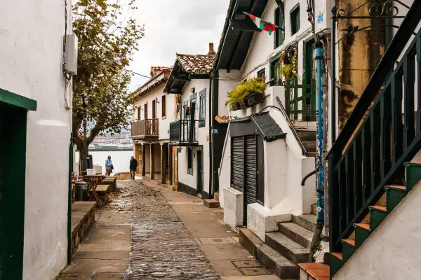 Calle empedrada con casas blancas y balcones de madera, ideal para pasear y descubrir qué ver en Algorta.