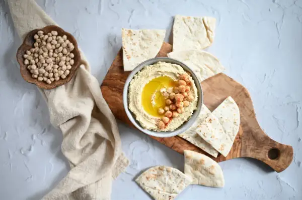 Miseczka kremowego hummusu z ciecierzycą i oliwą, podana z pitą. Czy hummus jest zdrowy? Tak, to pyszna i pożywna przekąska!
