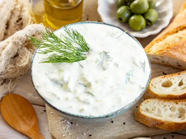 Cremiger Tzatziki mit Dill, serviert mit Baguette und Oliven. Ein einfaches Tzatziki Rezept für den Sommer.