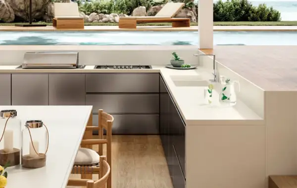 Moderna encimera para exterior con barbacoa integrada, junto a una piscina y tumbonas.