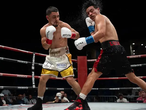 Two boxers clash in the ring. One lands a punch, sending sweat flying. This intense moment could lead to a unanimous decision in boxing if all judges score it for one fighter.