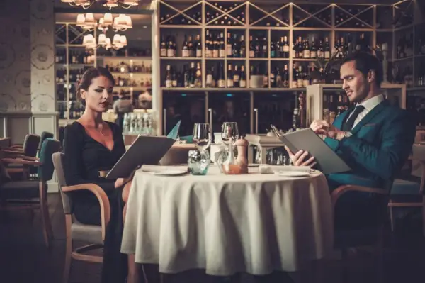 Elegancka para przy stoliku w restauracji, przegląda karty dań. Krótki dialog w restauracji po angielsku, co zamówić?